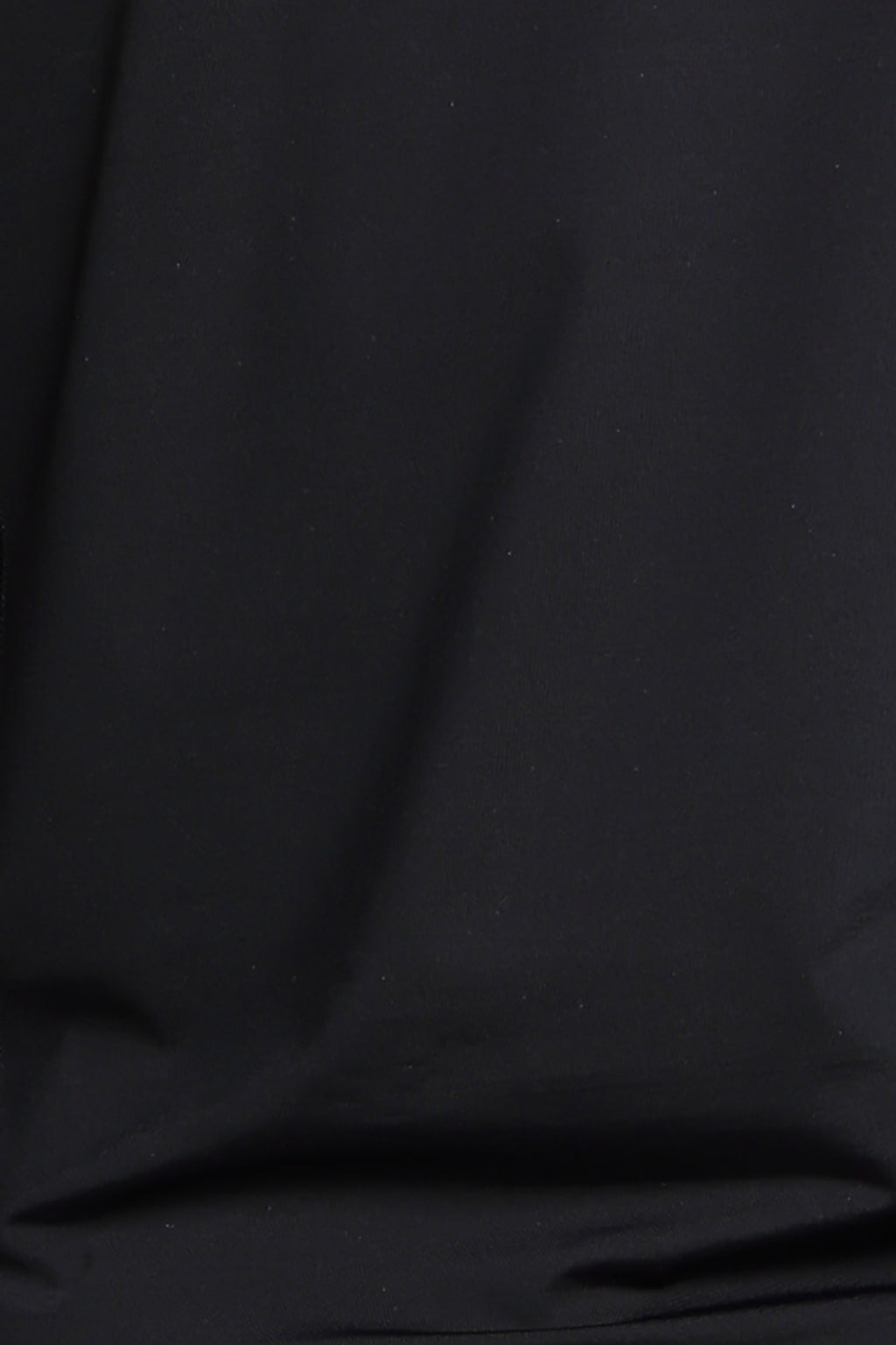A close-up of black fabric with soft folds and a smooth texture.