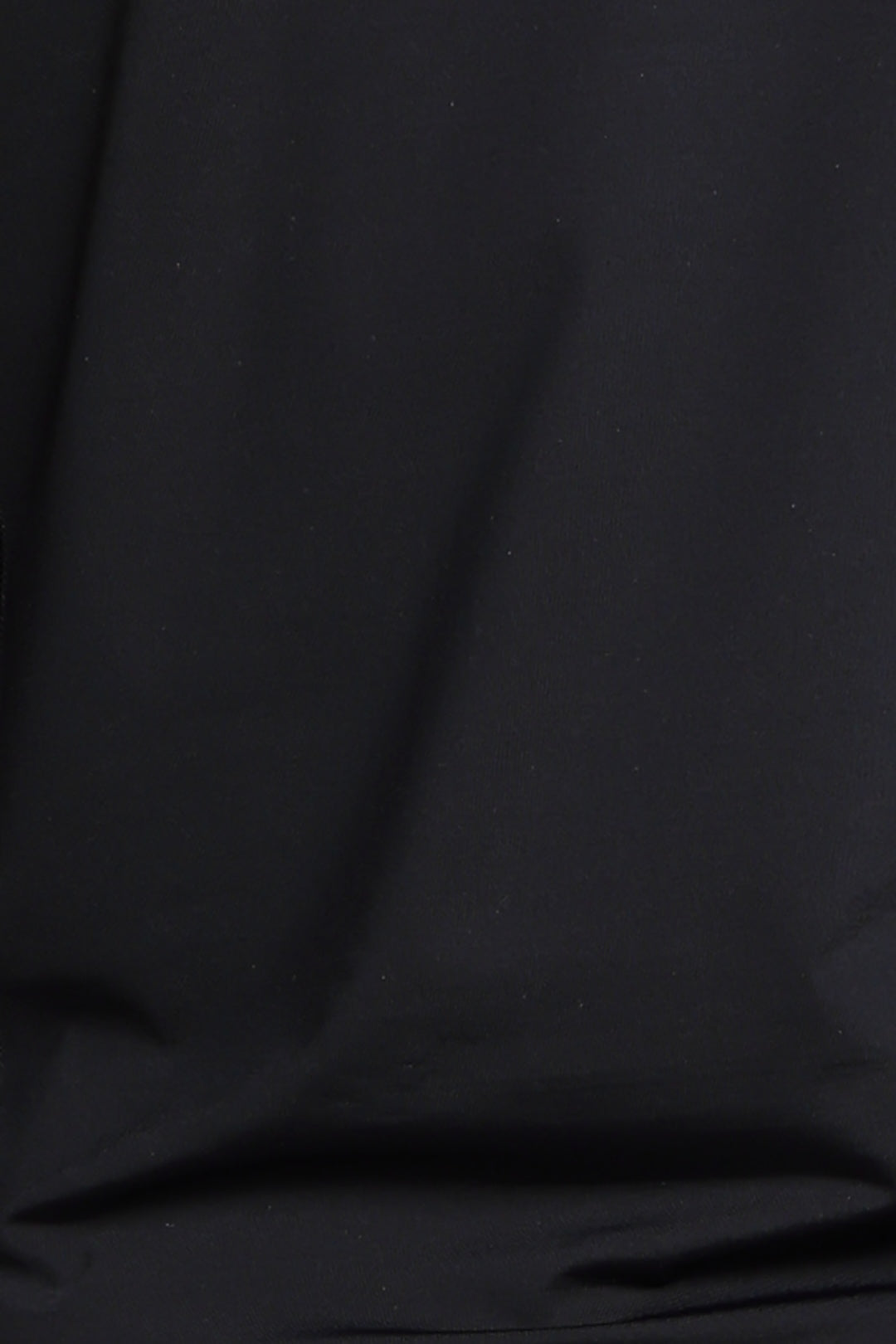 A close-up of black fabric with soft folds and a smooth texture.