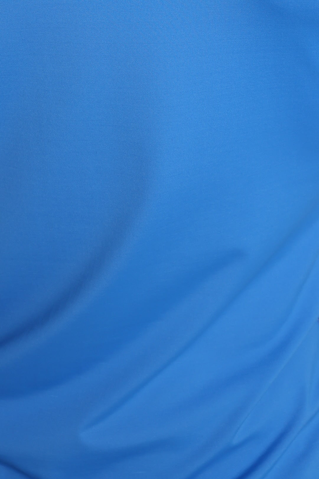 A close-up of a bright blue fabric surface with soft folds and no visible product edges or branding.