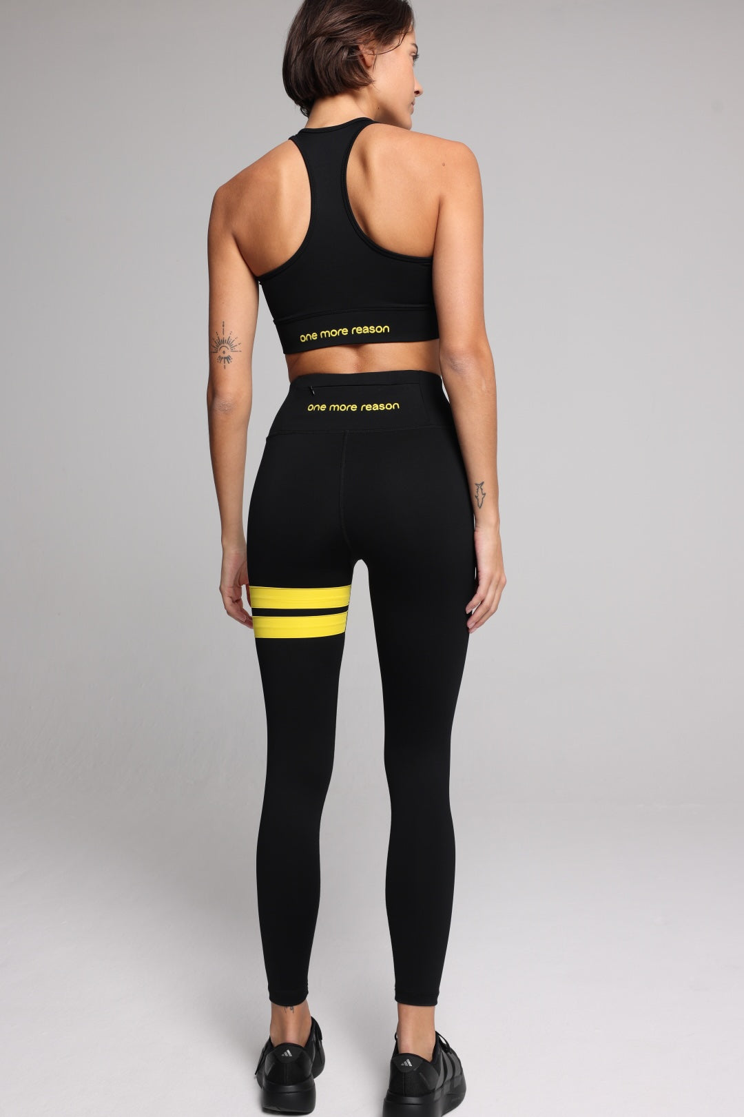 woman in black performance tank top and black leggings with yellow stripes top premium luxury activewear by One More Reason high-performance fitness apparel