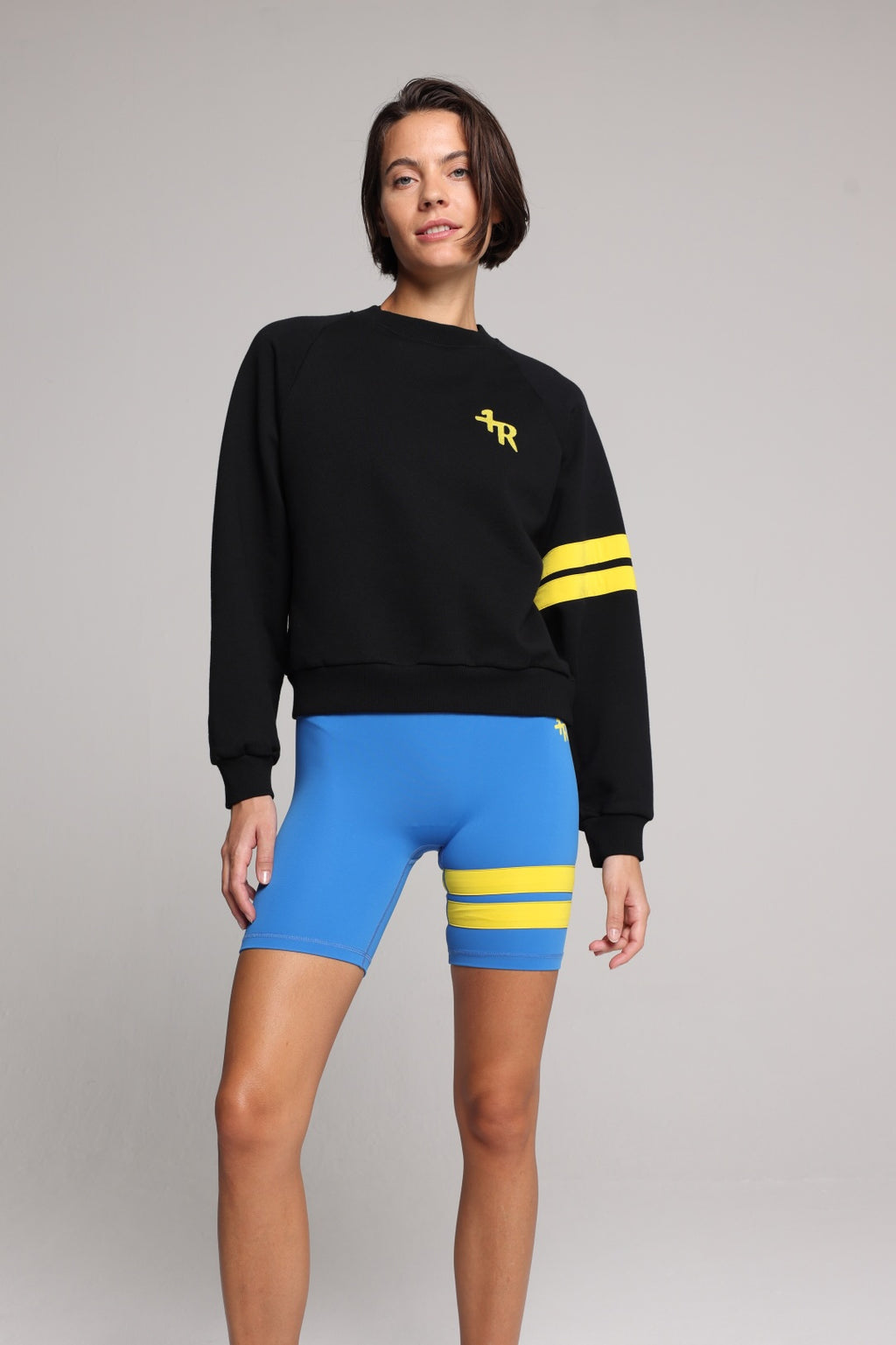 woman in black cotton crew sweater  and blue tights with yellow stripes top premium luxury activewear by One More Reason high-performance fitness apparel