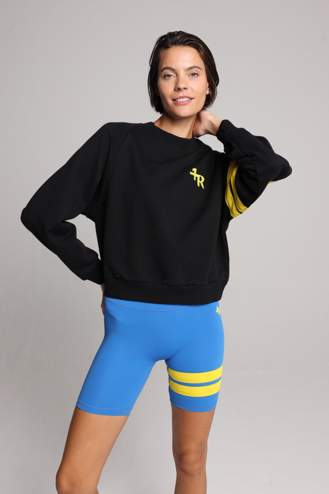 woman in black cotton crew sweater  and blue tights with yellow stripes top premium luxury activewear by One More Reason high-performance fitness apparel