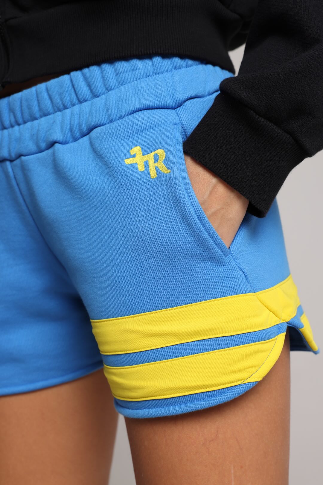 Blue shorts with yellow accents and a logo on the pocket by one more reason