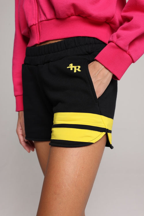 woman wearing a premium cotton pink hoodie with a blue hood and black shorts with yellow stripes by one more reason studio set up