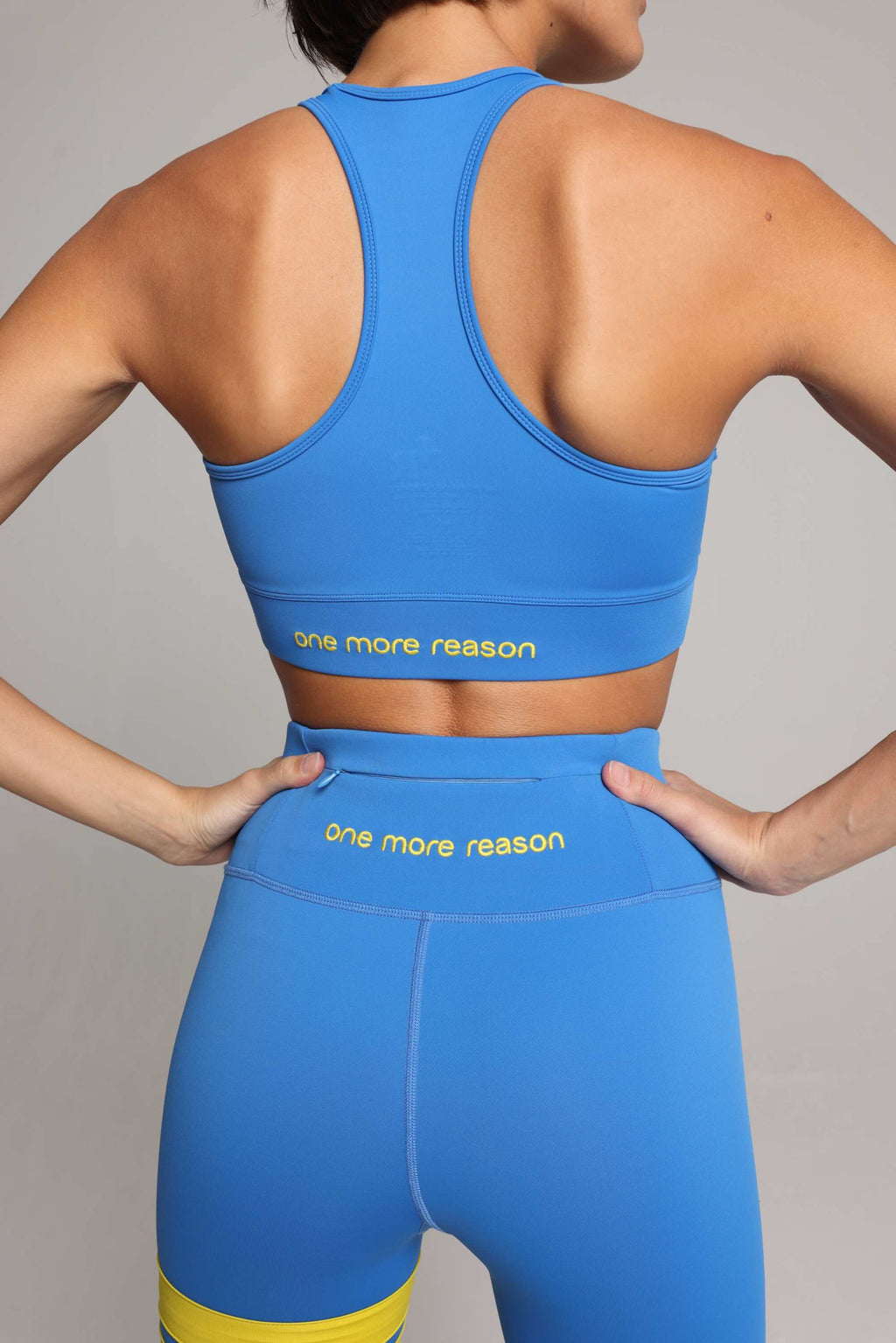 Back view of a women wearing premi blue high-waisted leggings and blue tank top by One More Reason premium fashion forward sports wear 