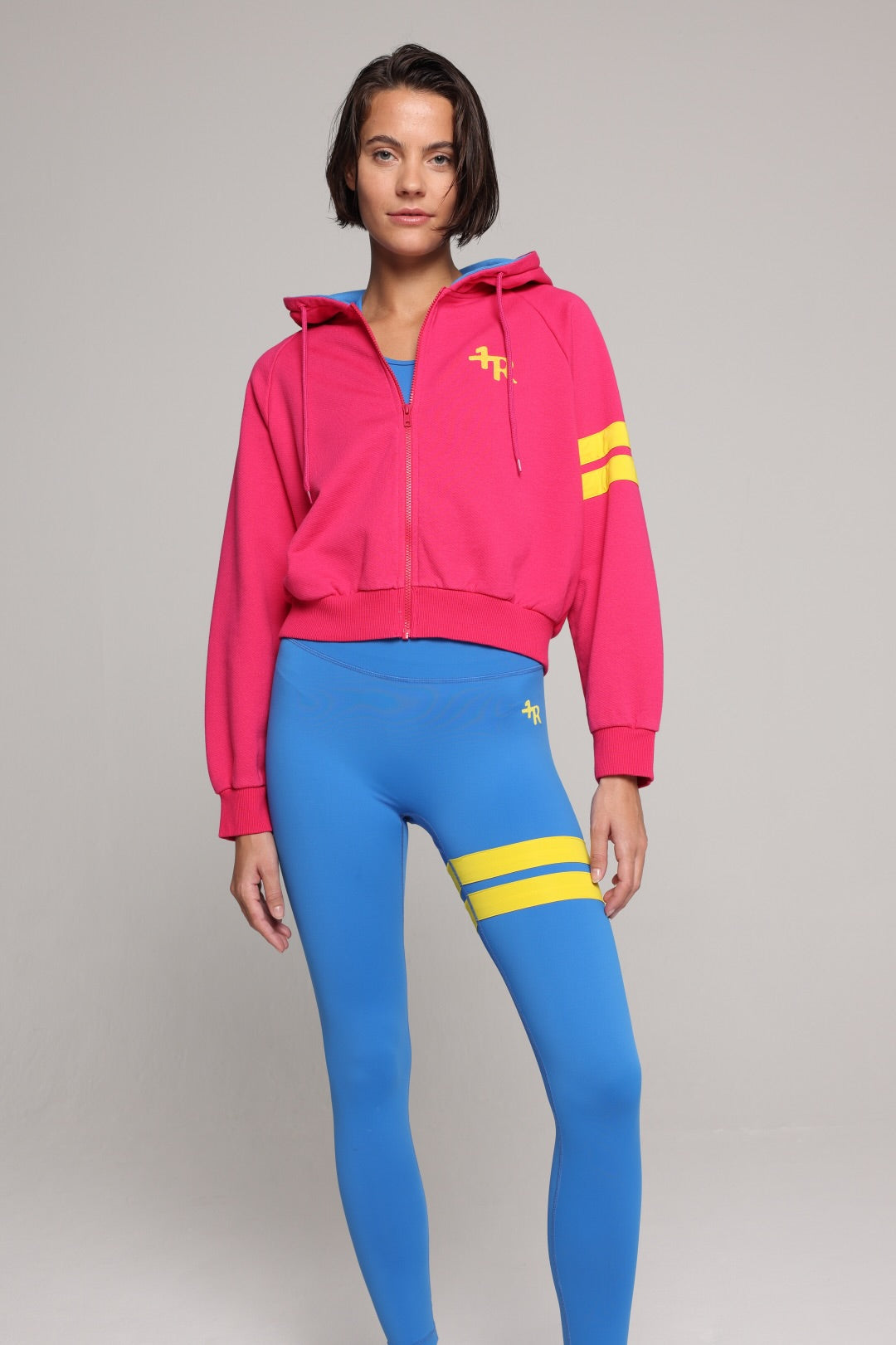 woman wearing bicolor organic cotton zip hoodie in pink and blue and blue tights  with yellow stripes by One More Reason, women's luxury activewear indoor set