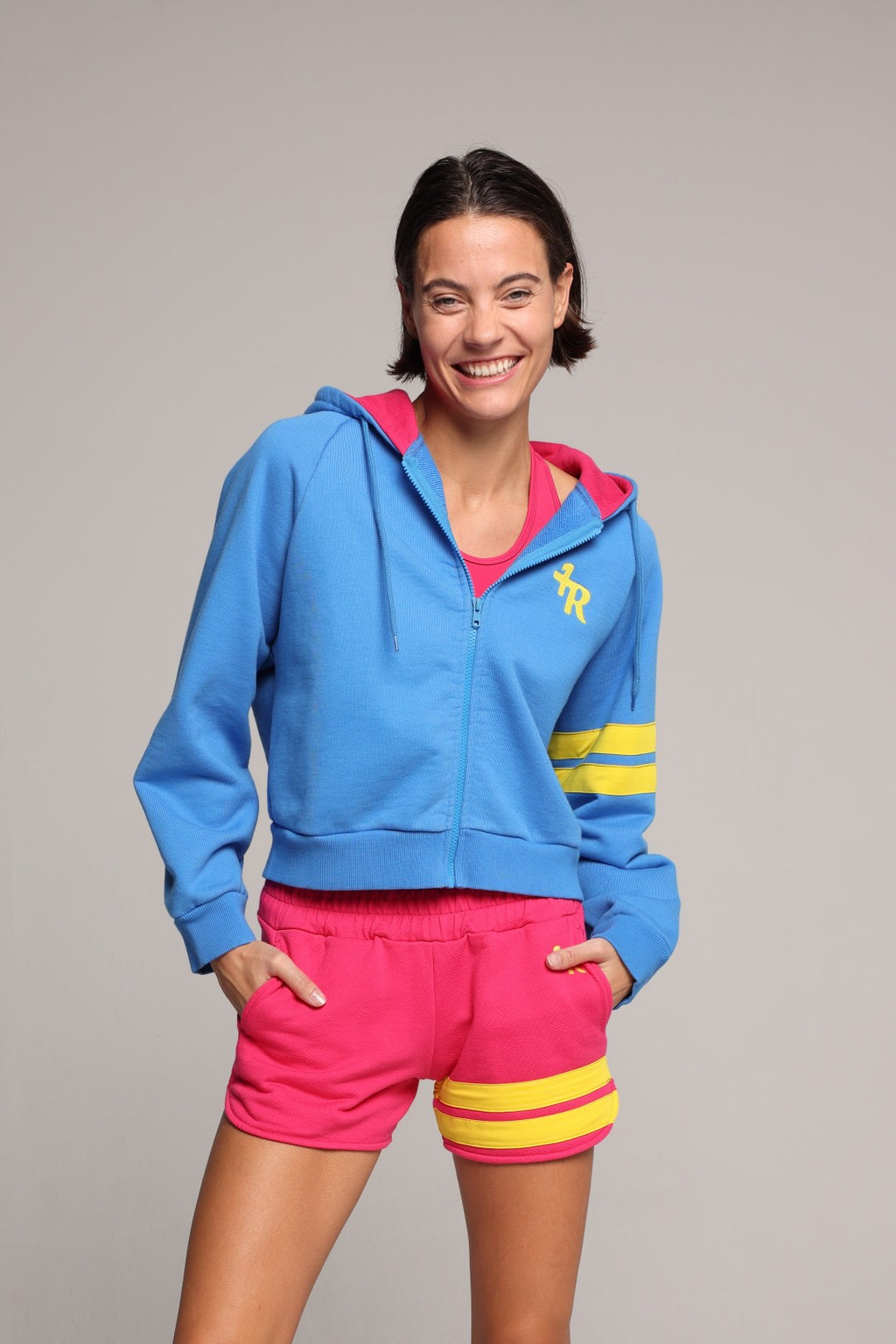 Woman wearing a blue hoodie and pink shorts with yellow stripes studio set