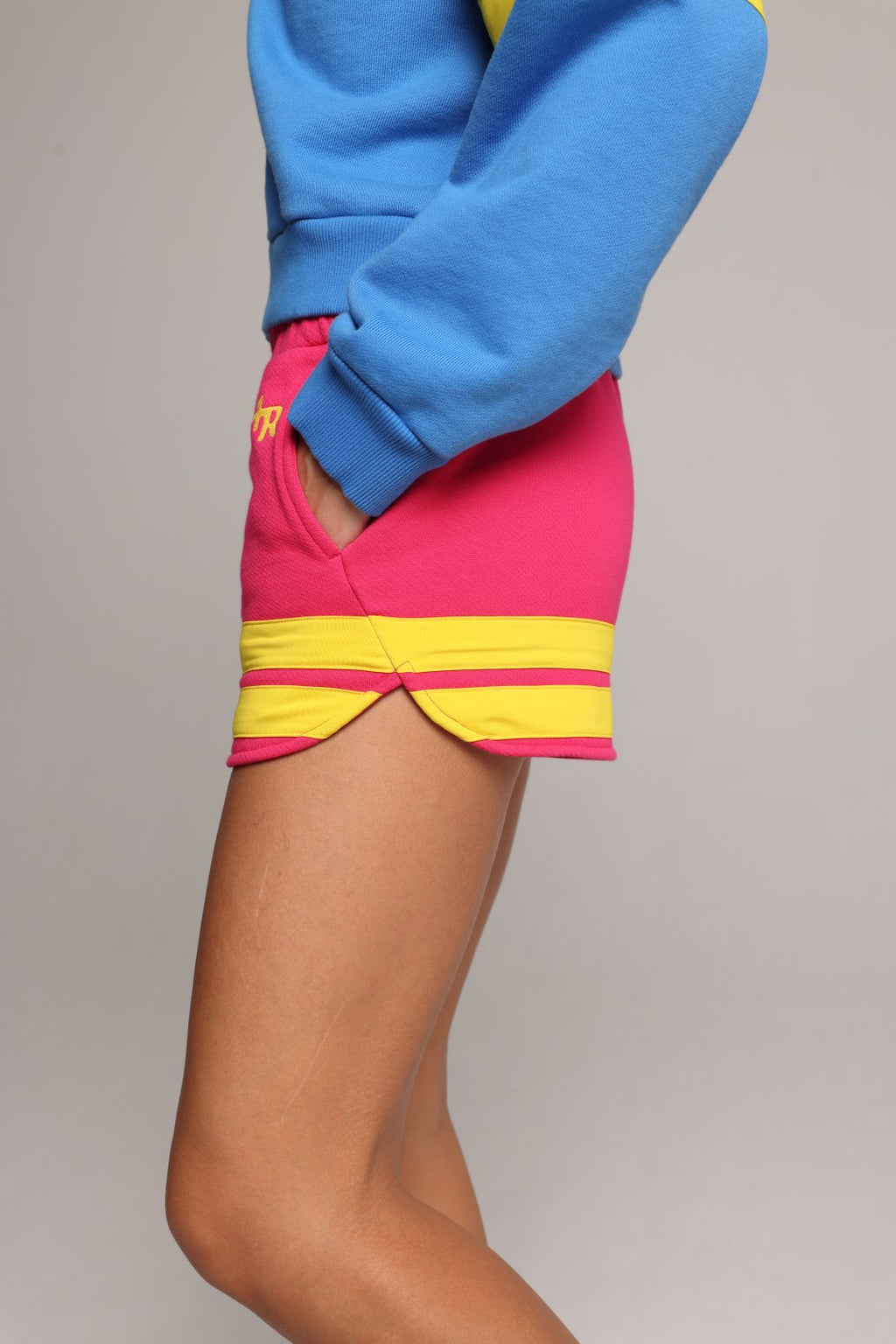 woman wearing pink cotton shorts with yellow stripes and a blue hoodie by one more reason premium sportswear studio set