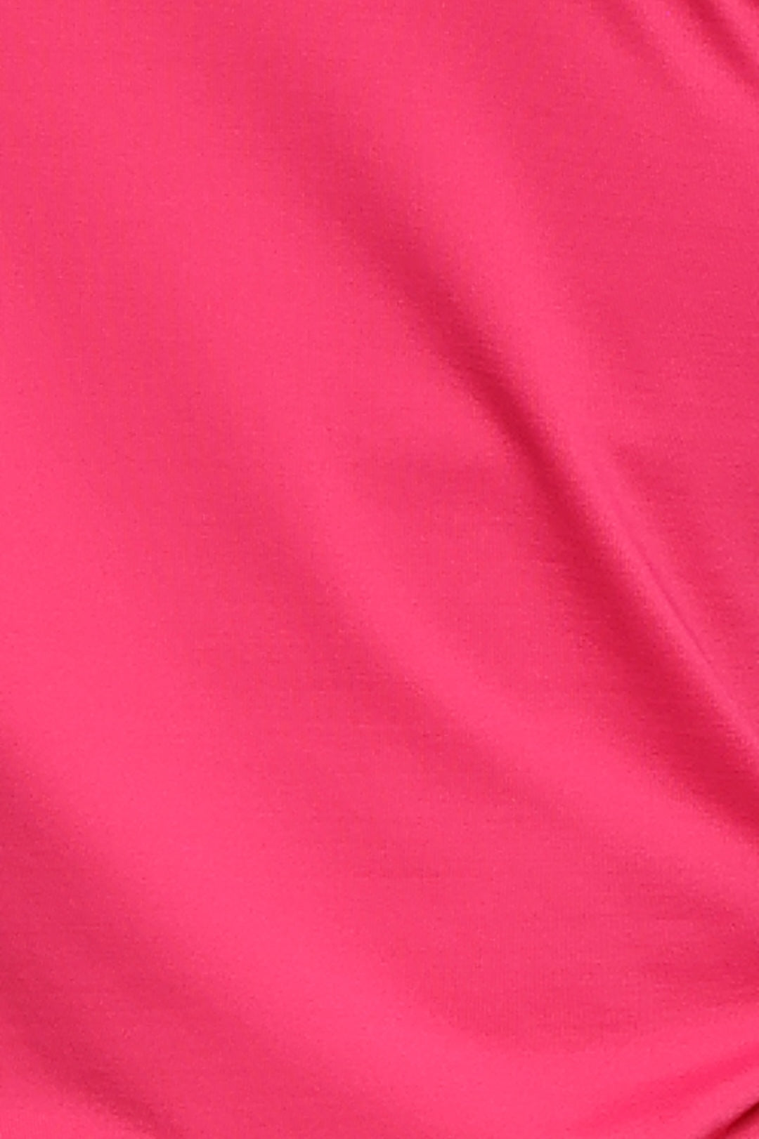 A close-up of bright pink fabric with soft folds and a smooth texture.