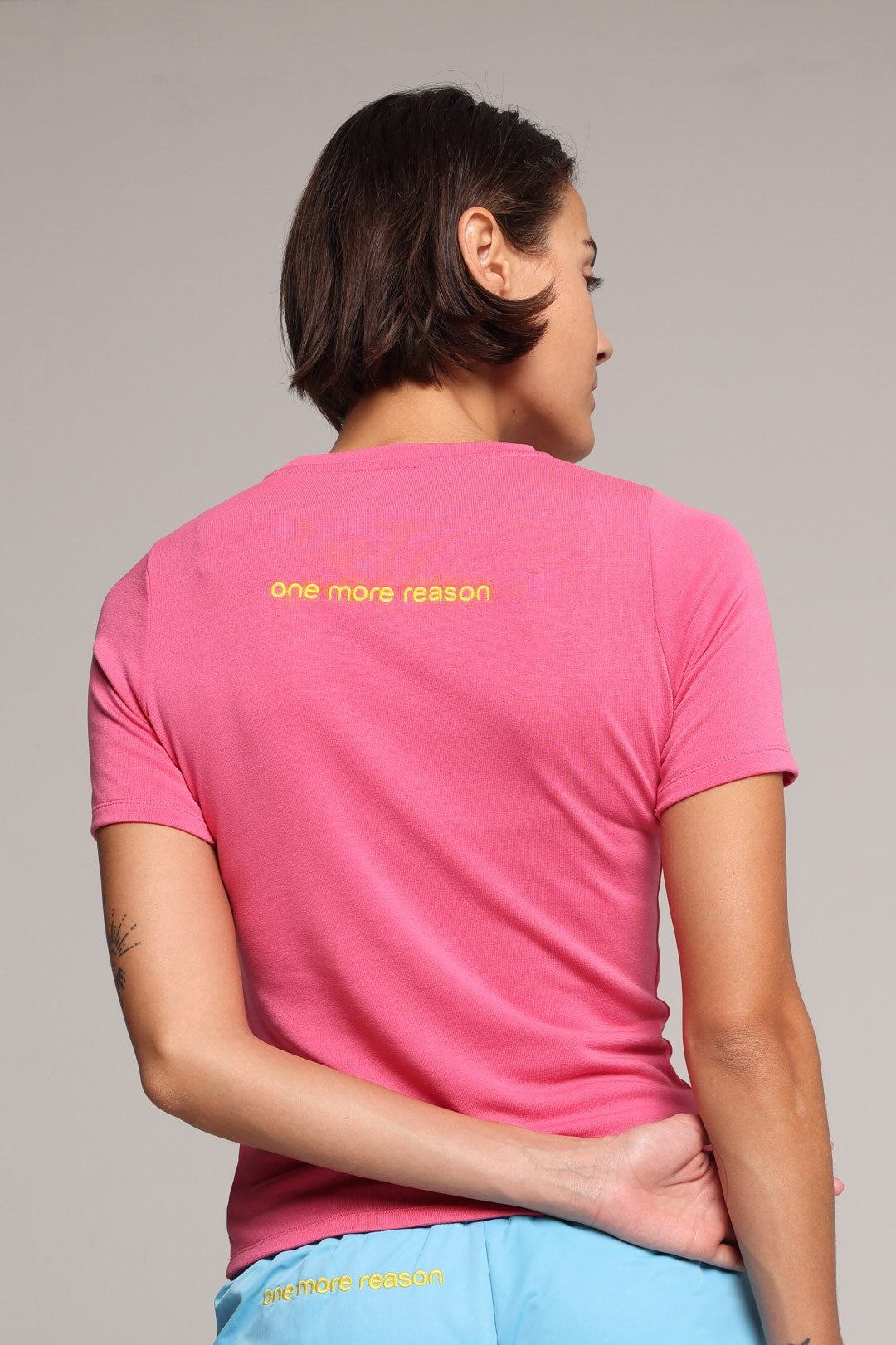 woman wearing a pink t-shirt with a yellow logo by one more reason
