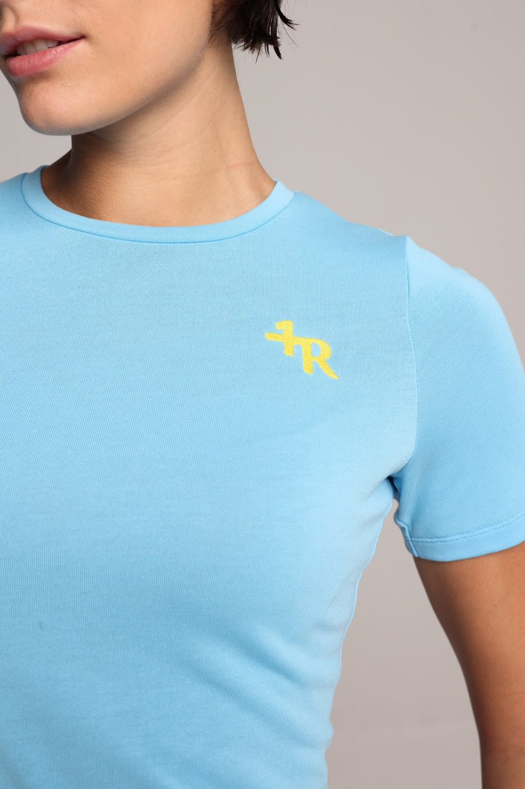 Light blue t-shirt with a yellow logo by one more reason worn by a woman