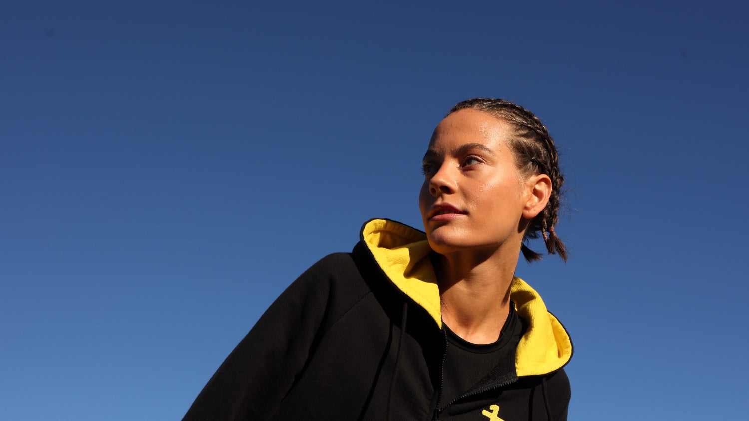 Woman wearing  black luxury athletic performance jacket by  One More Reason, with yellow stripes, outdoor set up