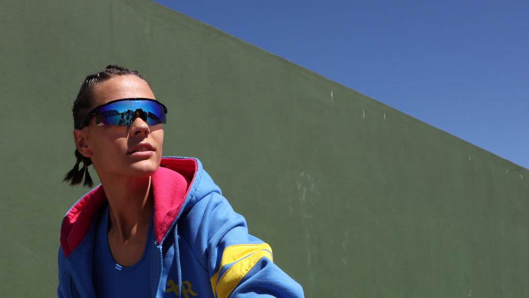 woman wearing blue and pink sports outfit blue leggings and sports jacket with yellow signature stripes by one more reason outdoor setting
