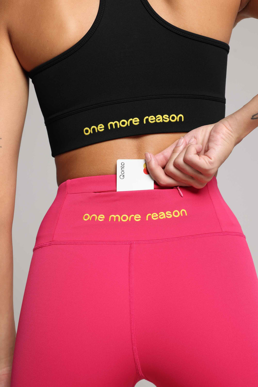 Women wearing black performance tank top and pink shorts by One More Reason, women's activewear studio set, back view.