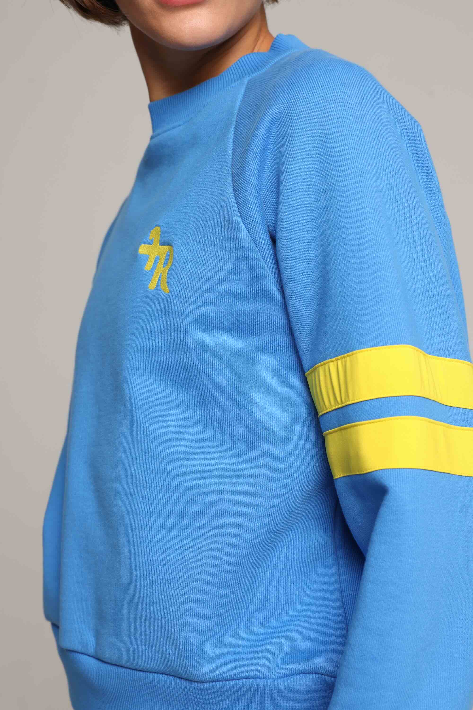 Close-up of  blue oversized crew sweater with yellow stripes by One More Reason, studio close-up.