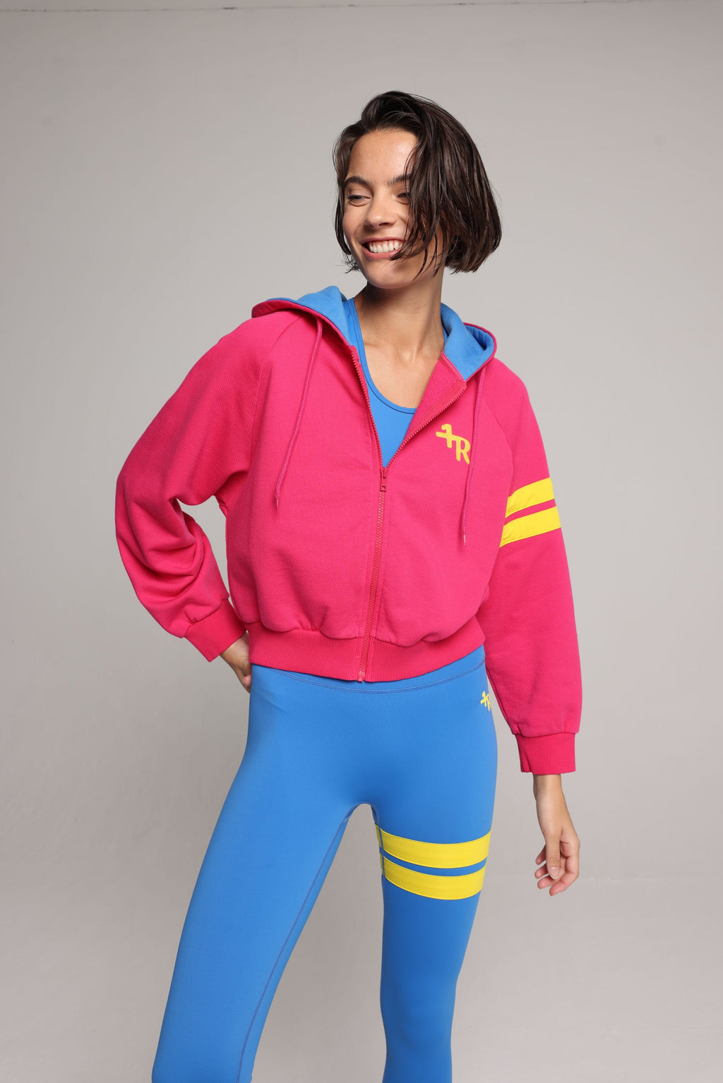 woman wearing bicolor organic cotton zip hoodie in pink and blue and blue tights  with yellow stripes by One More Reason, women's luxury activewear indoor set