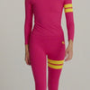 Woman in pink leggings and long sleeve top with yellow stripes by One More Reason is doing pilates.