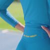 Woman in blue leggings and a blue long sleeve top with yellow stripes by One More Reason is running in a stadium.