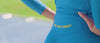 Woman in blue leggings and a blue long sleeve top with yellow stripes by One More Reason is running in a stadium.