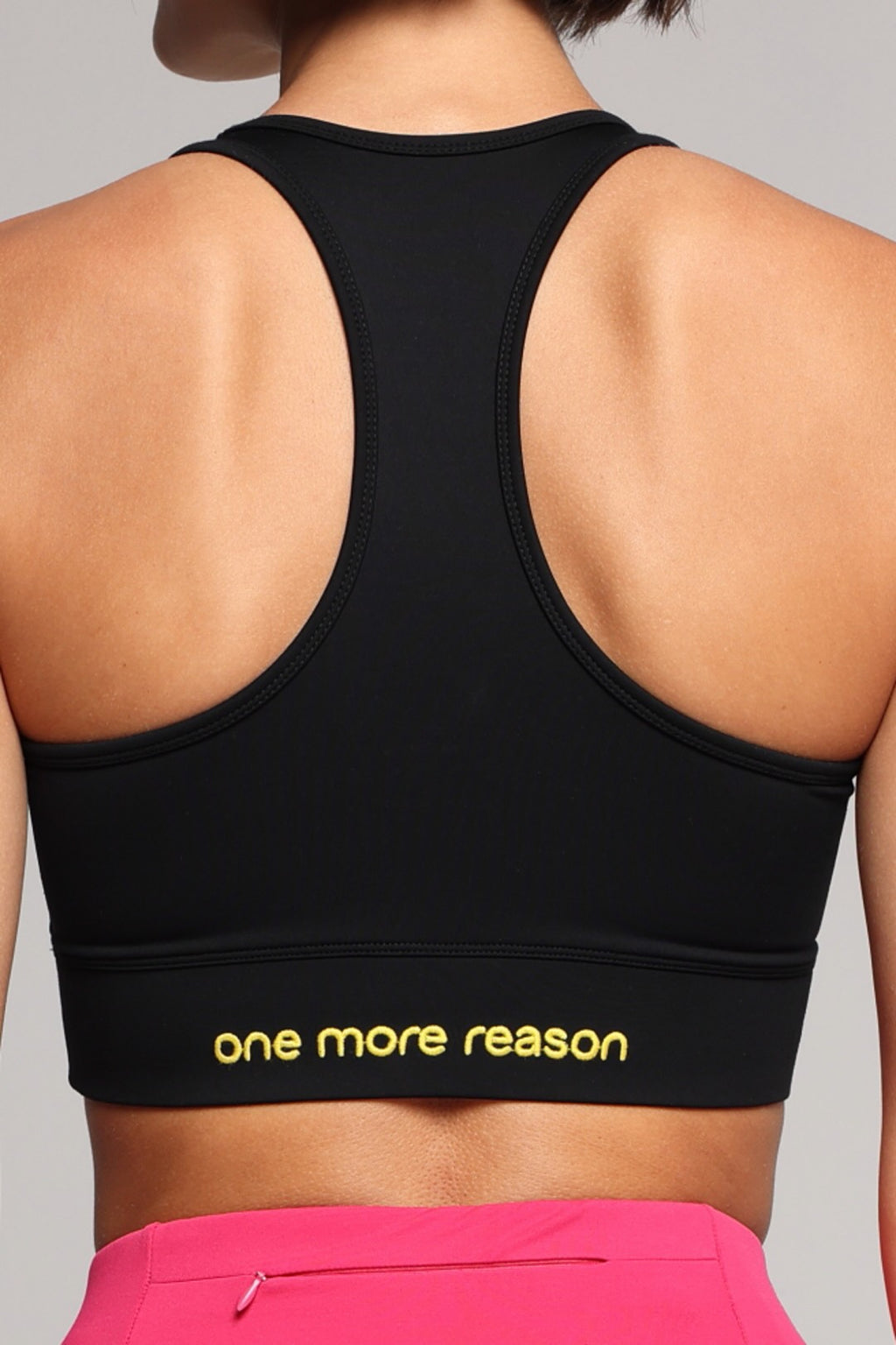 Rear view of a woman wearing a black sports bra. Premium Sportswear by One More Reason.
