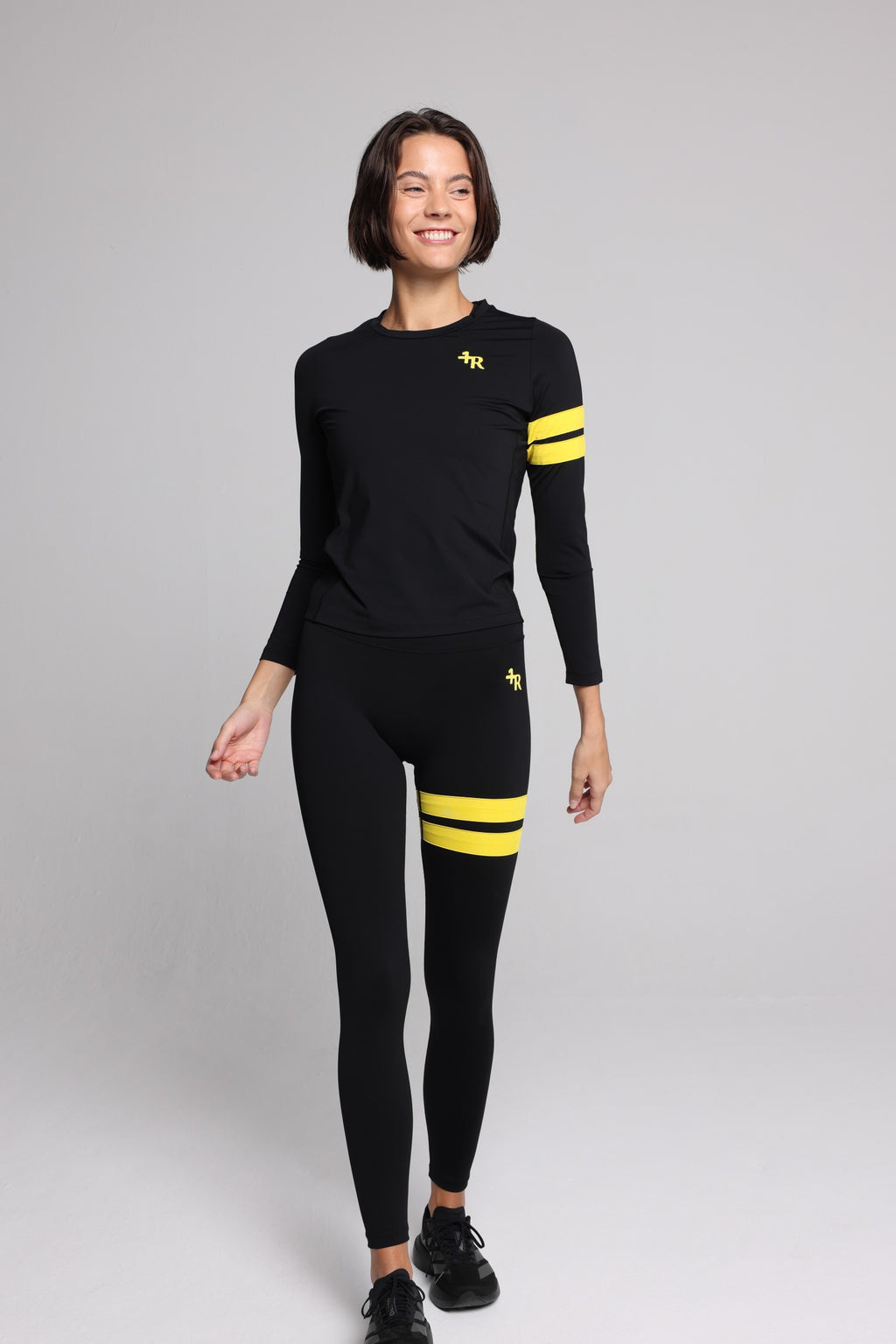 women in black long-sleeve performance top and black leggings with yellow stripes top premium luxury activewear by One More Reason high-performance fitness apparel
