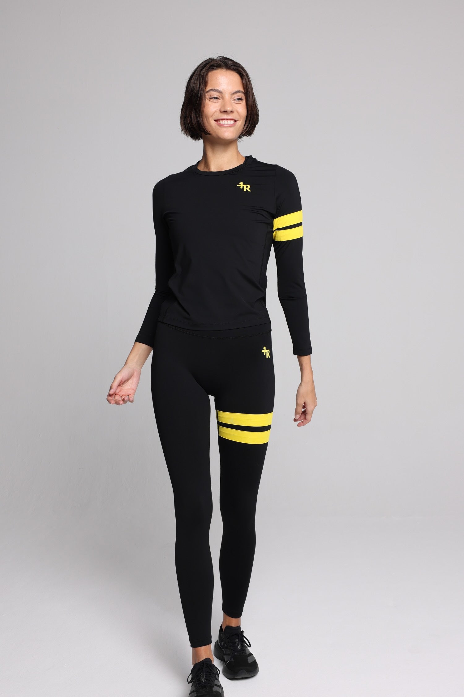 women in black long-sleeve performance top and black leggings with yellow stripes top premium luxury activewear by One More Reason high-performance fitness apparel