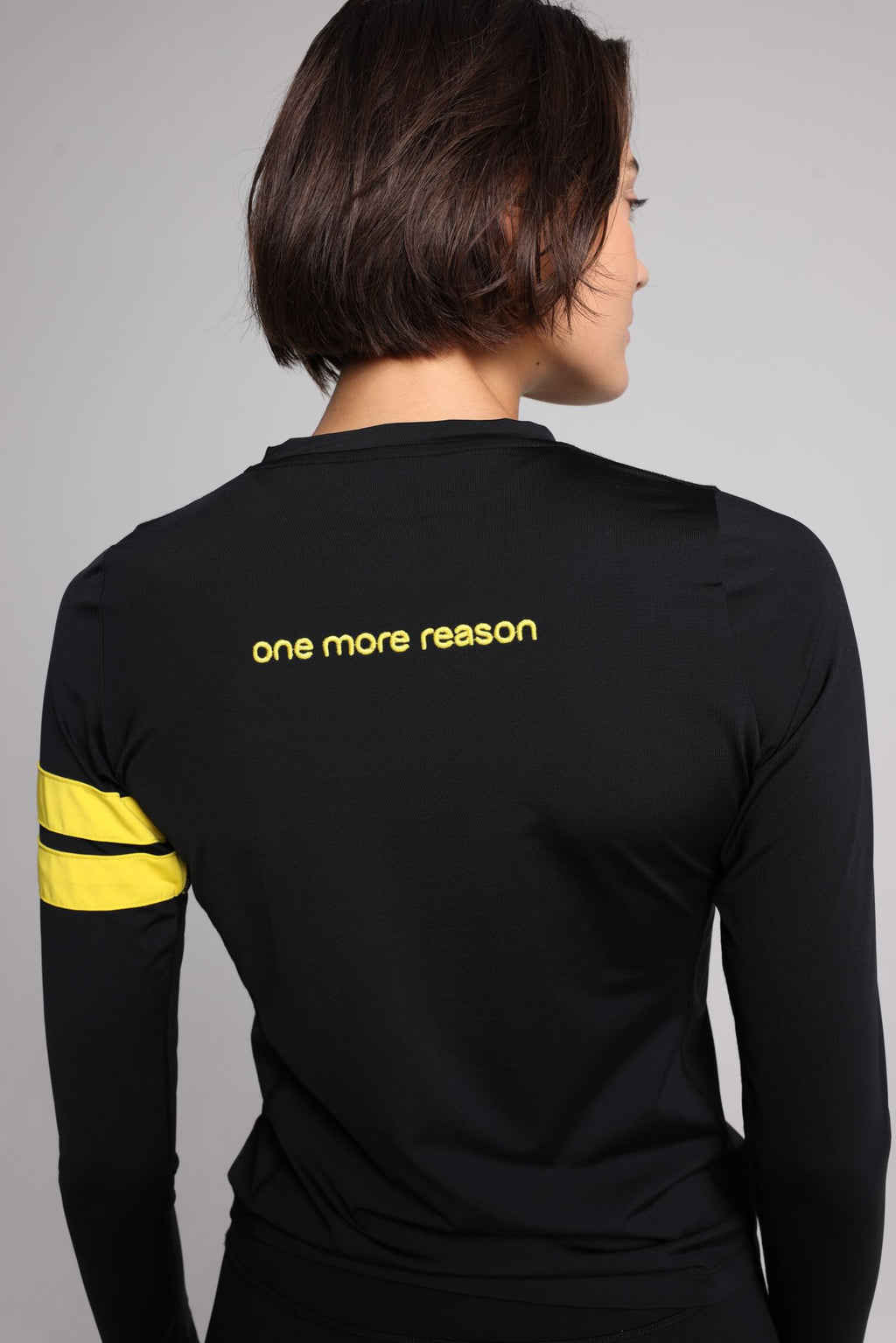 women in black long sleeve performance top with yellow stripes top premium luxury activewear by One More Reason high-performance fitness apparel back view
