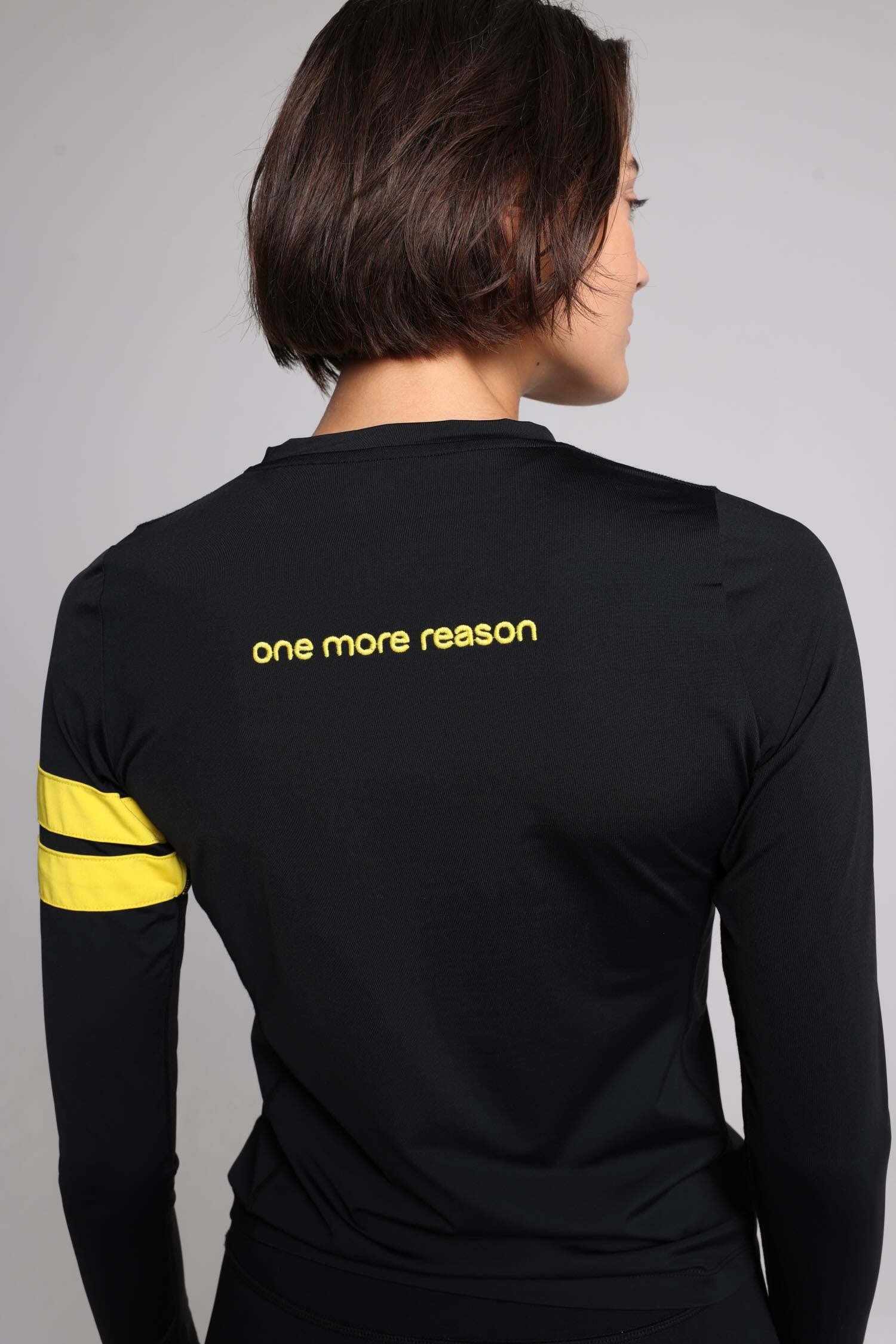women in black long sleeve performance top with yellow stripes top premium luxury activewear by One More Reason high-performance fitness apparel back view