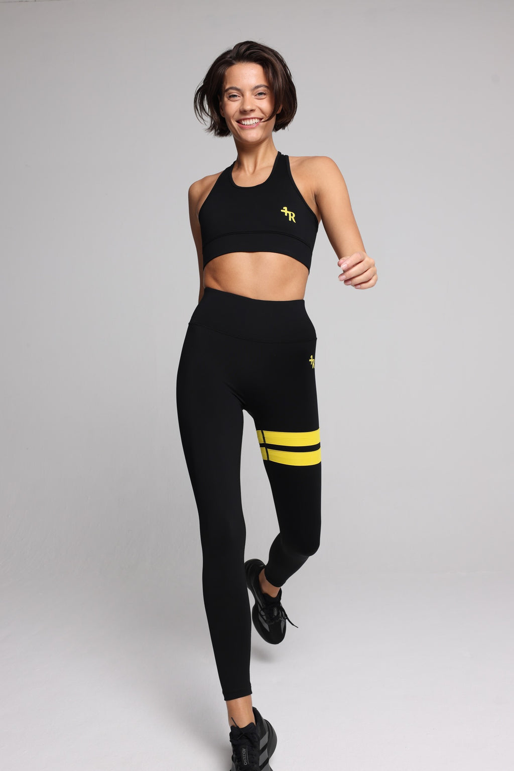 woman in black performance tank top and black leggings with yellow stripes top premium luxury activewear by One More Reason high-performance fitness apparel