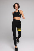 woman in black performance tank top and black leggings with yellow stripes top premium luxury activewear by One More Reason high-performance fitness apparel