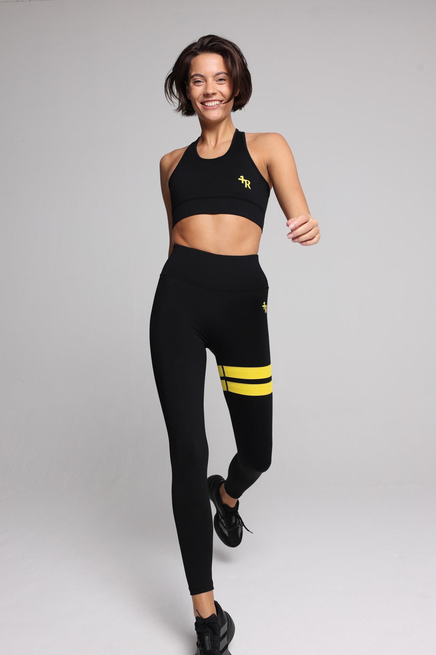 woman in black performance tank top and black leggings with yellow stripes top premium luxury activewear by One More Reason high-performance fitness apparel