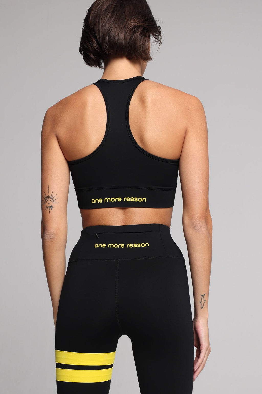 women in black sport tank  and black leggings with yellow stripes top premium luxury activewear by One More Reason high-performance fitness apparel back view