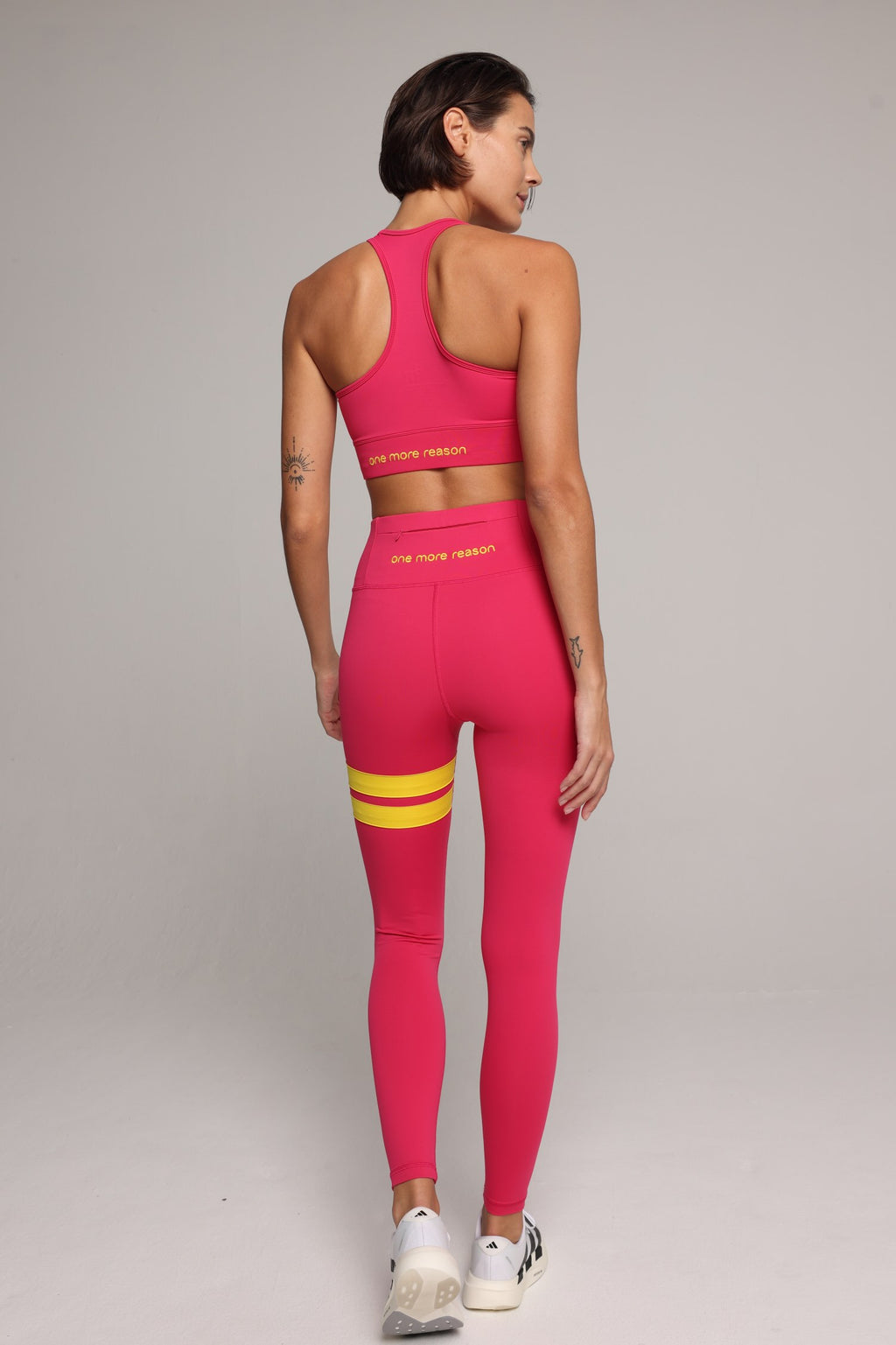 woman wearing premium pink tank top and pink leggings with yellow stripes by One More Reason, women's luxury activewear indoor set back view
