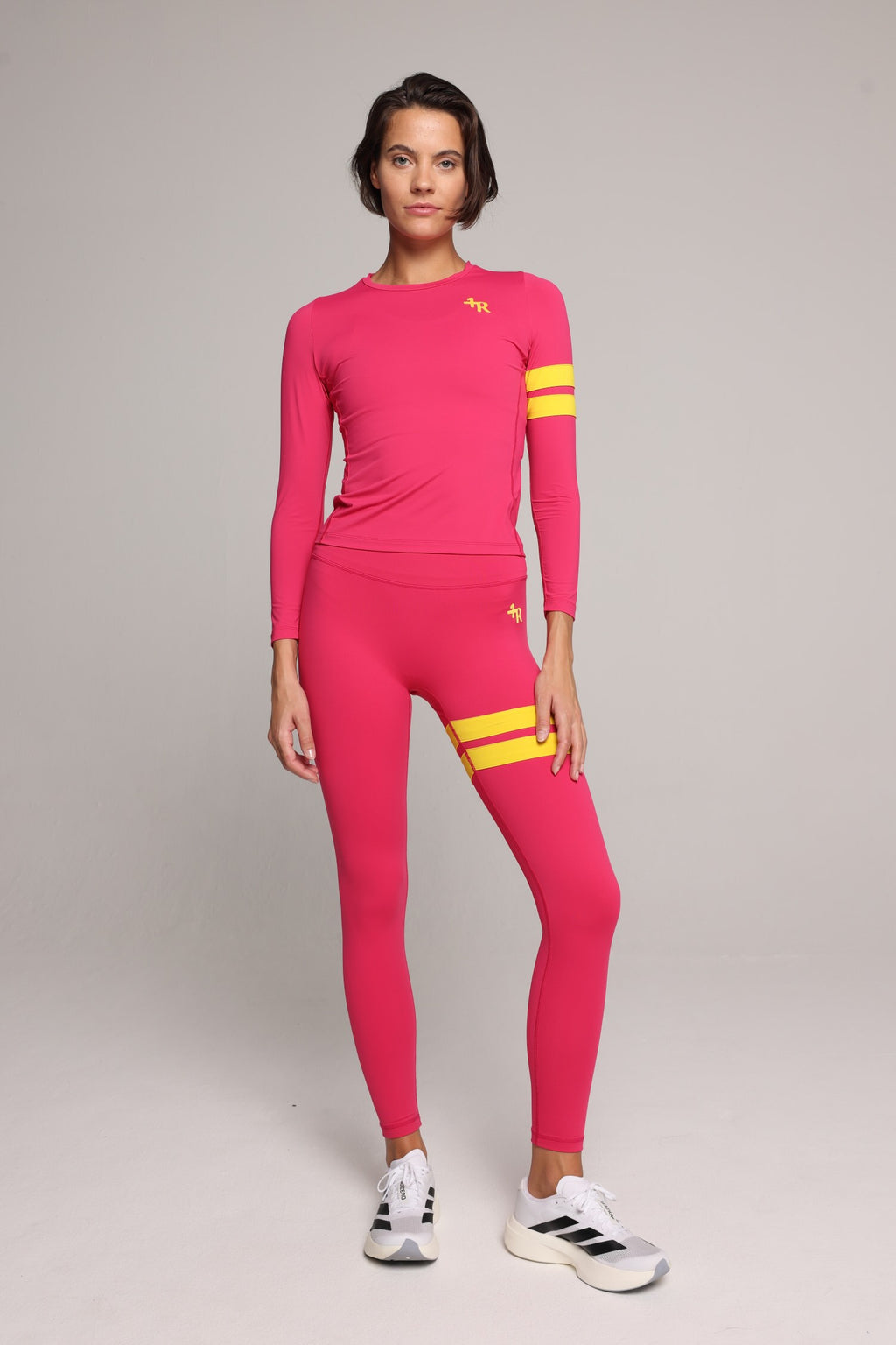 Woman wearing premium pink long sleeve top and pink performance leggings with yellow stripes by One More Reason luxury women's activewear indoor set