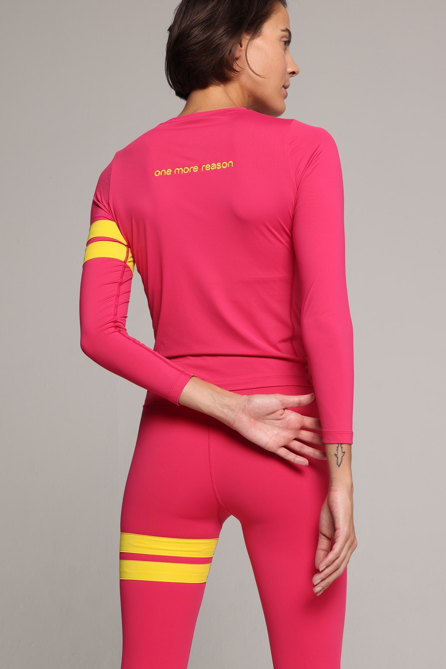 woman wearing premium pink long sleeve top and pink performance leggings with yellow stripes by One More Reason luxury women's activewear indoor set back view