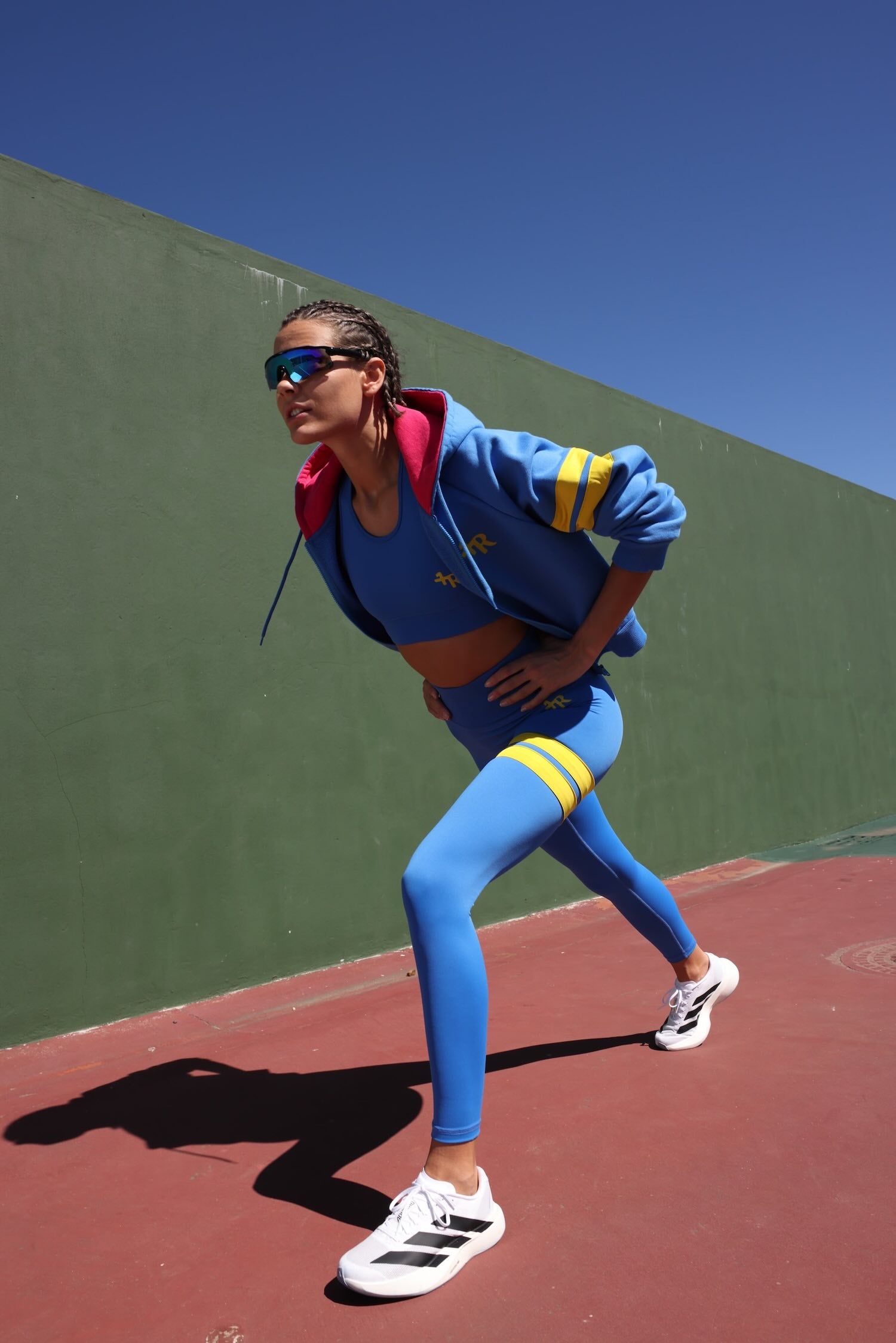 woman in premium blue sports outfit blue high-waisted leggings with yellow stripes and blue pink sports jacket by One More Reason